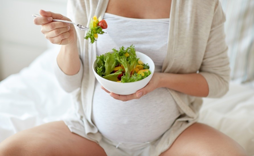 Pregnant woman eating salad. Pregnant woman eating salad.